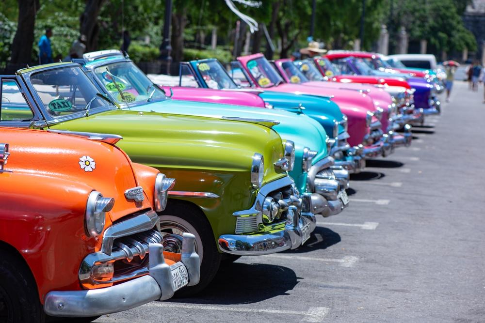 A line of parked Vintage Cars of different colors in a row.
